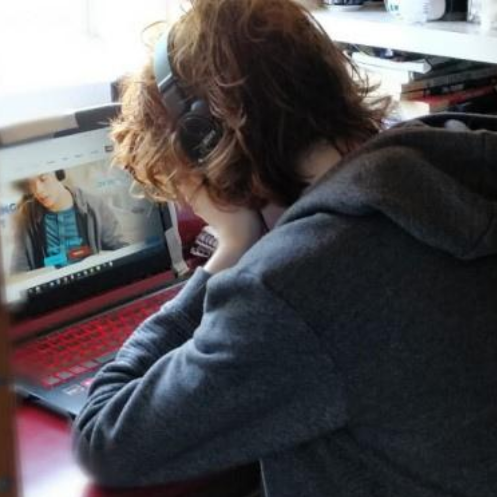 Young person sat at laptop with head in hands