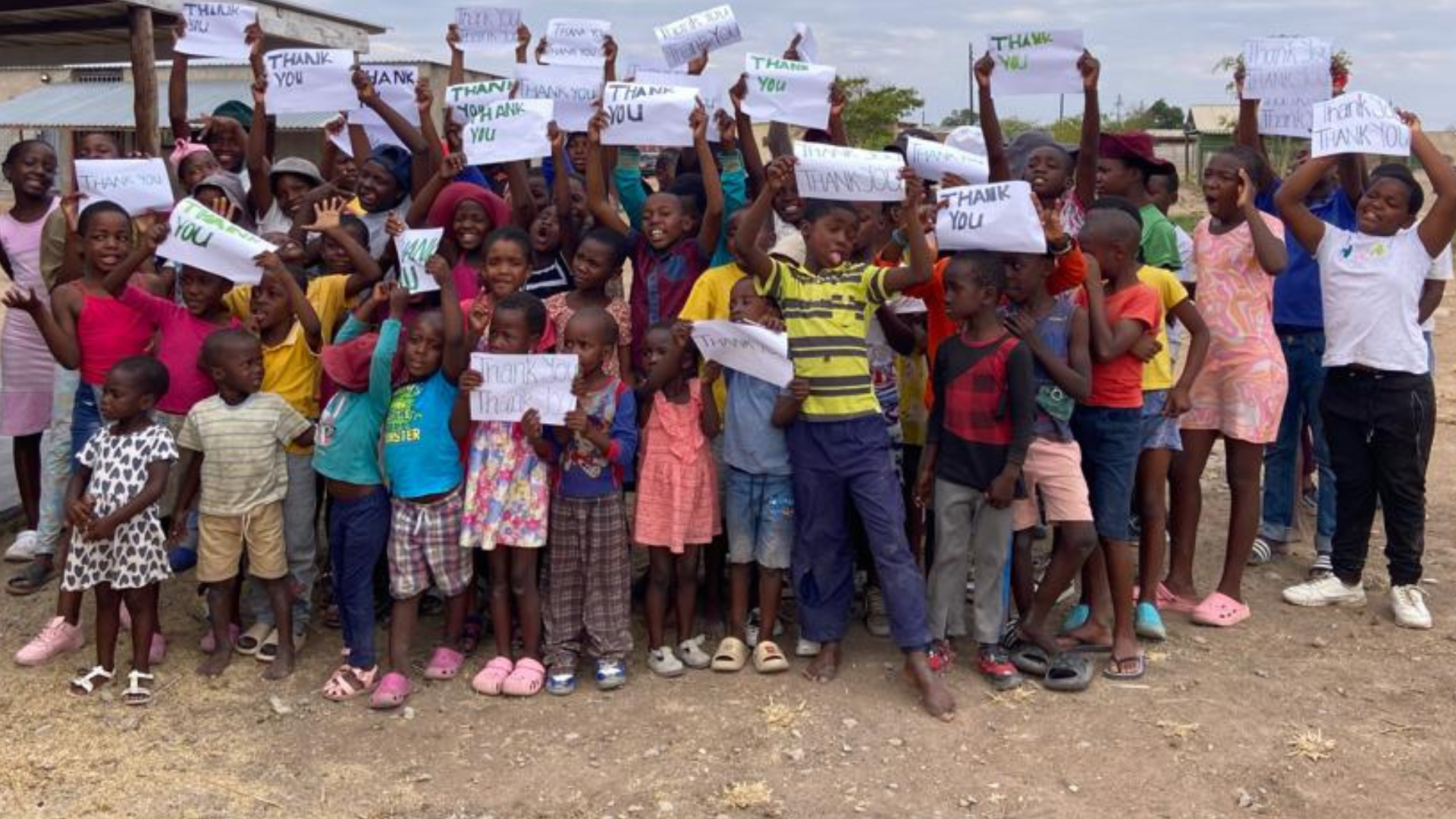 Group of children holding up signs that say Thank You