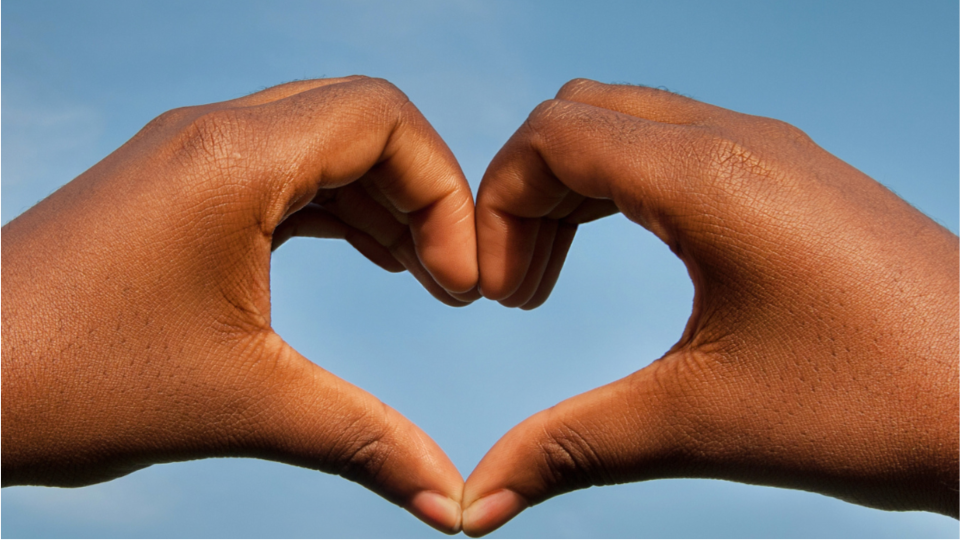 A child's hands forming the shape of a heart with fingers and thumbs