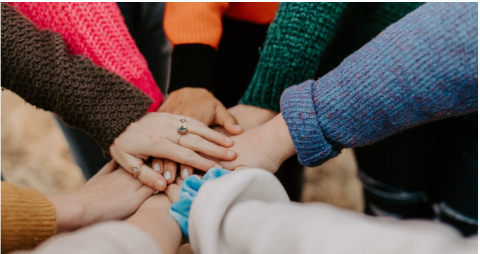 Young people putting hands together in a circle